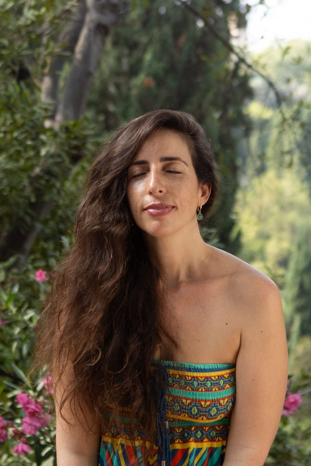 Portrait of Einat in a garden, eyes closed, smiling softly